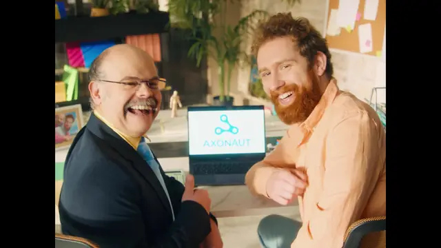 Un entrepreneur et son comptable rient devant un ordinateur portable affichant le logo Axonaut