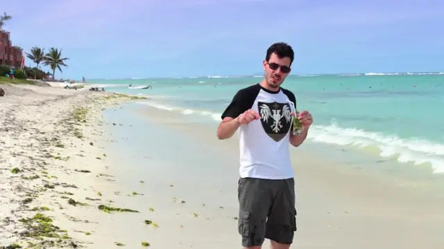 Un créateur YouTube sur une plage de sable blanc au bord d'une eau turquoise