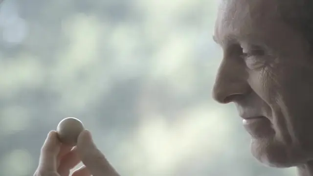 Gros plan d'un artisan âgé tenant une boule de pétanque, film Chronopost