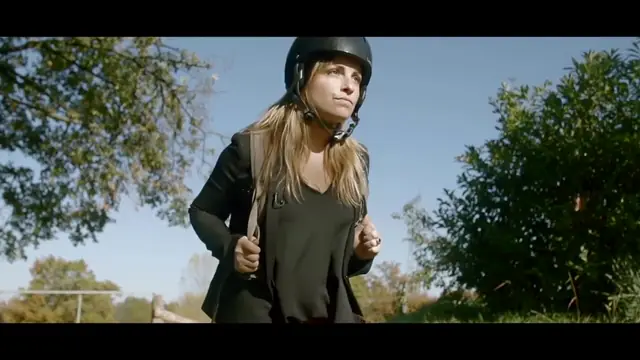 Une éco-reporter casquée devant un camion-grue de collecte